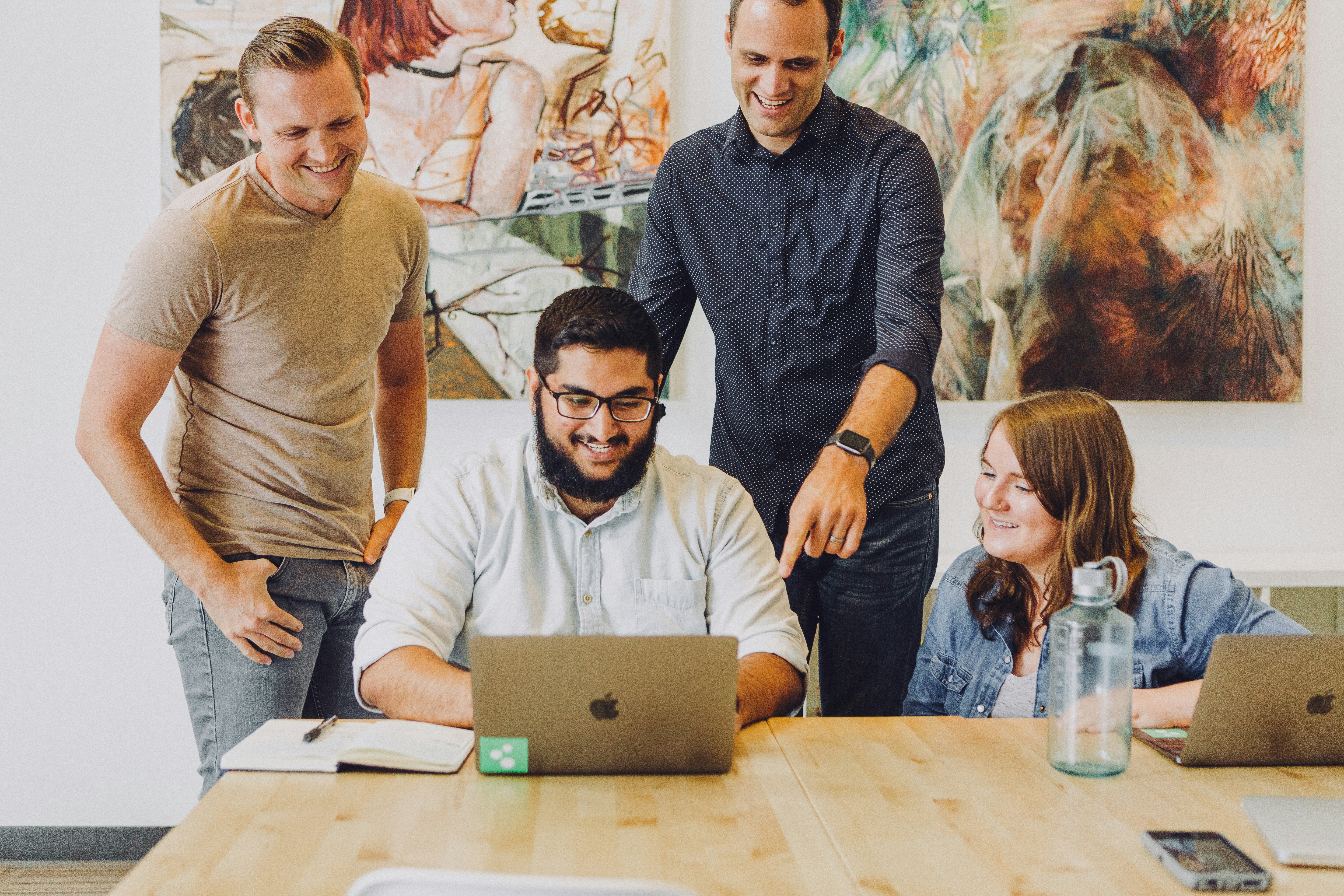 Image of four people looking at a laptop